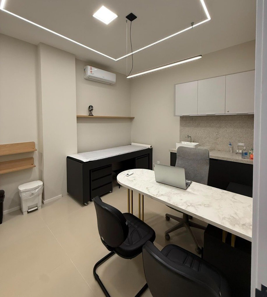 Consultório com mesa de atendimento e maca para avaliação