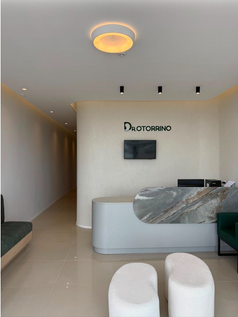 Recepção da clínica com balcão curvo, logotipo e poltronas